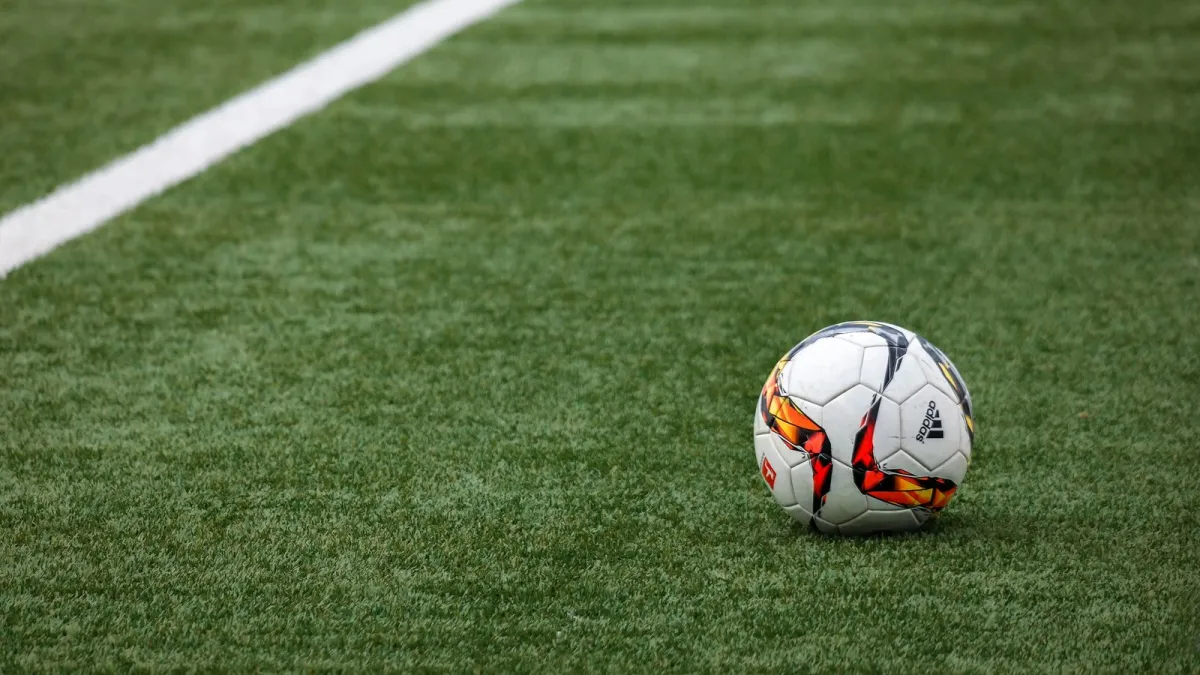 Match ball resting on the grass beside a painted white line